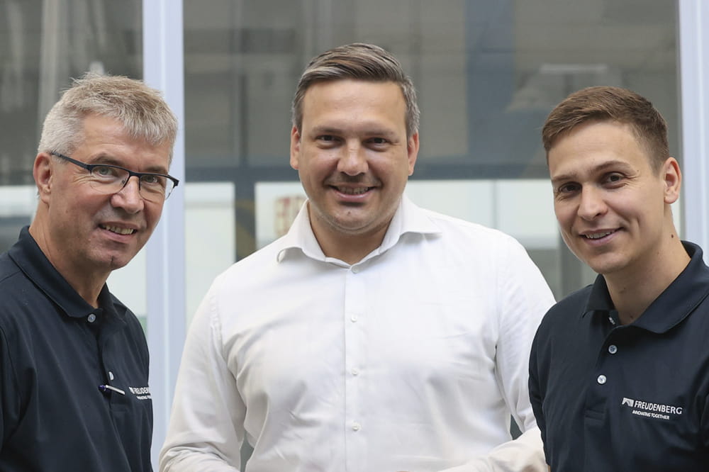 Three men look into the camera smiling.